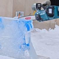 person with chainsaw against block of ice